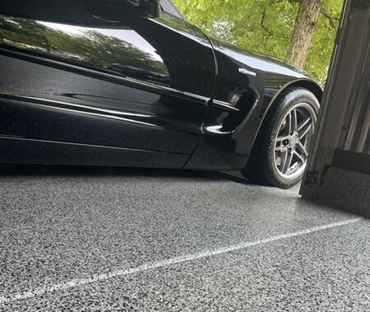Concrete coating on garage floor with a black car in the garage.