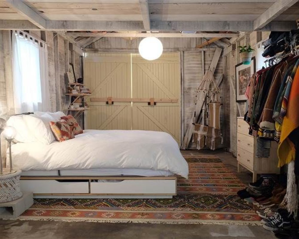 white bed in a garage with clothes hanging on the wall